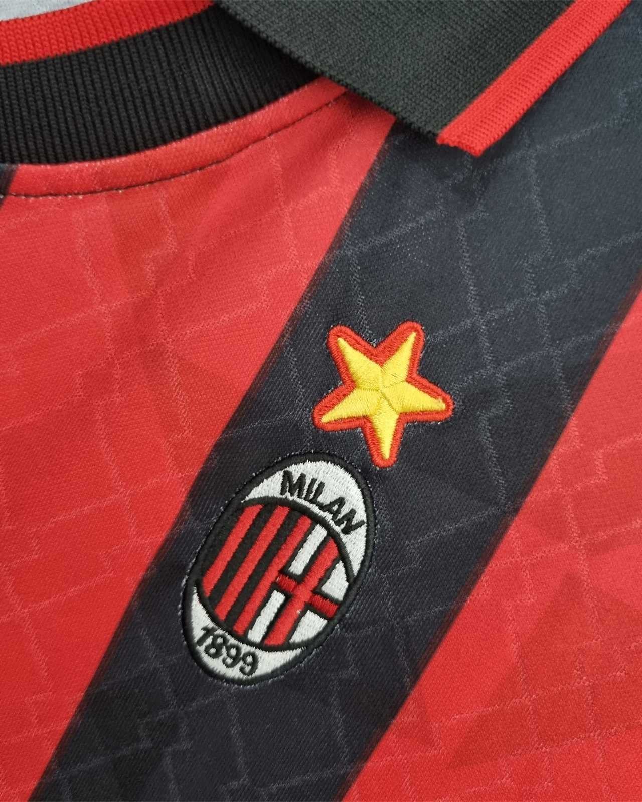 Dettaglio dello stemma del Milan con stella dorata su tessuto a strisce rosse e nere.