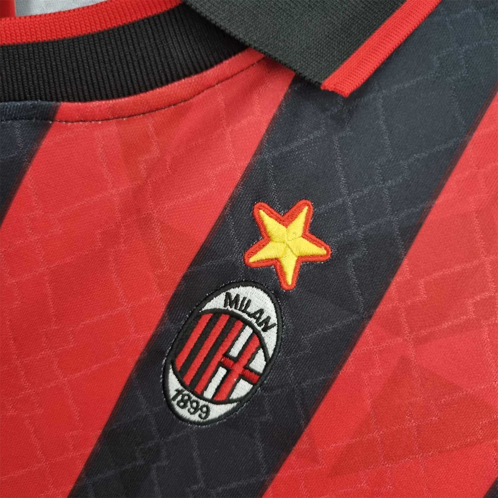 Dettaglio dello stemma del Milan con stella dorata su tessuto a strisce rosse e nere.
