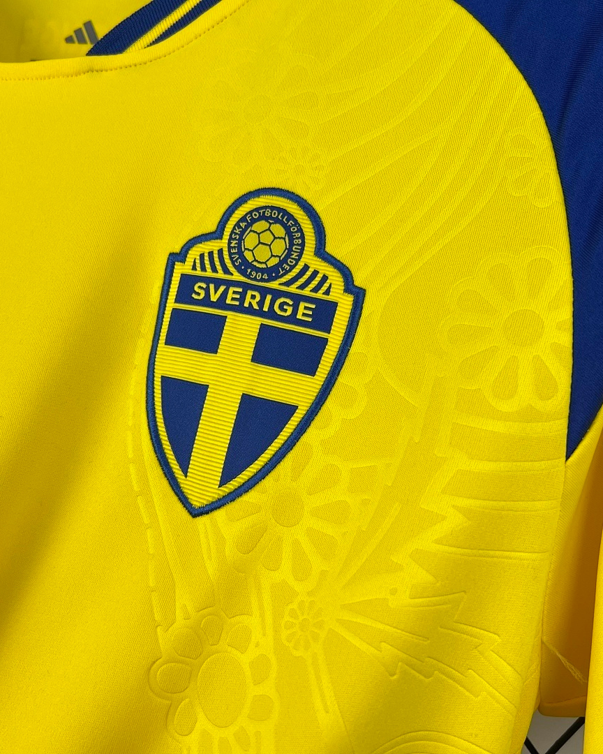 Dettaglio stemma Svezia e texture floreale su maglia home 2026