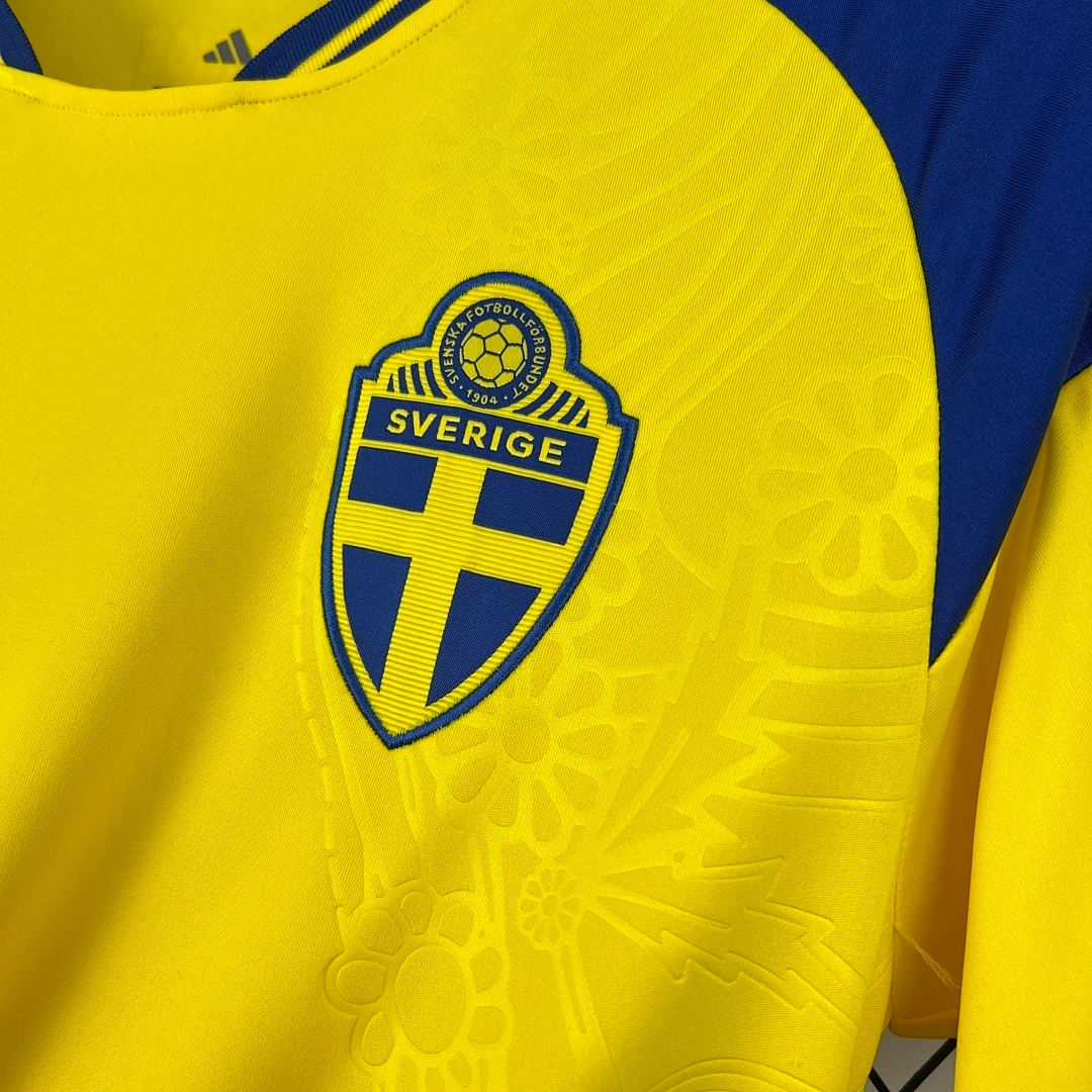 Dettaglio stemma Svezia e texture floreale su maglia home 2026
