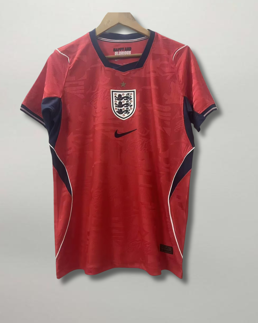 Fronte della maglia away dell'Inghilterra 2026 scura con dettagli geometrici colorati sui fianchi e stemma ricamato