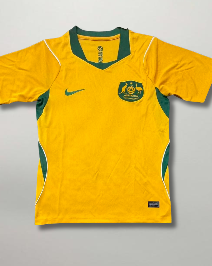 Fronte della maglia home dell'Australia 2026 oro con inserti verdi e stemma ufficiale ricamato sul petto