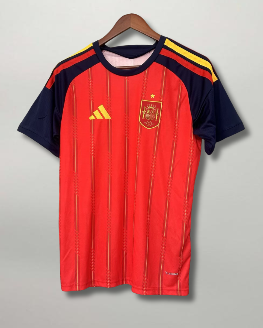 Fronte della maglia home della Spagna 2026 rossa con pannelli scuri sulle maniche e stemma sul petto