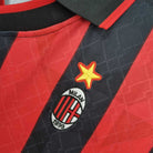 Dettaglio dello stemma del Milan con stella dorata su tessuto a strisce rosse e nere.