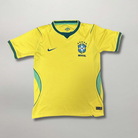 Fronte della maglia home del Brasile 2026 giallo oro con dettagli verdi e stemma stellato sul petto