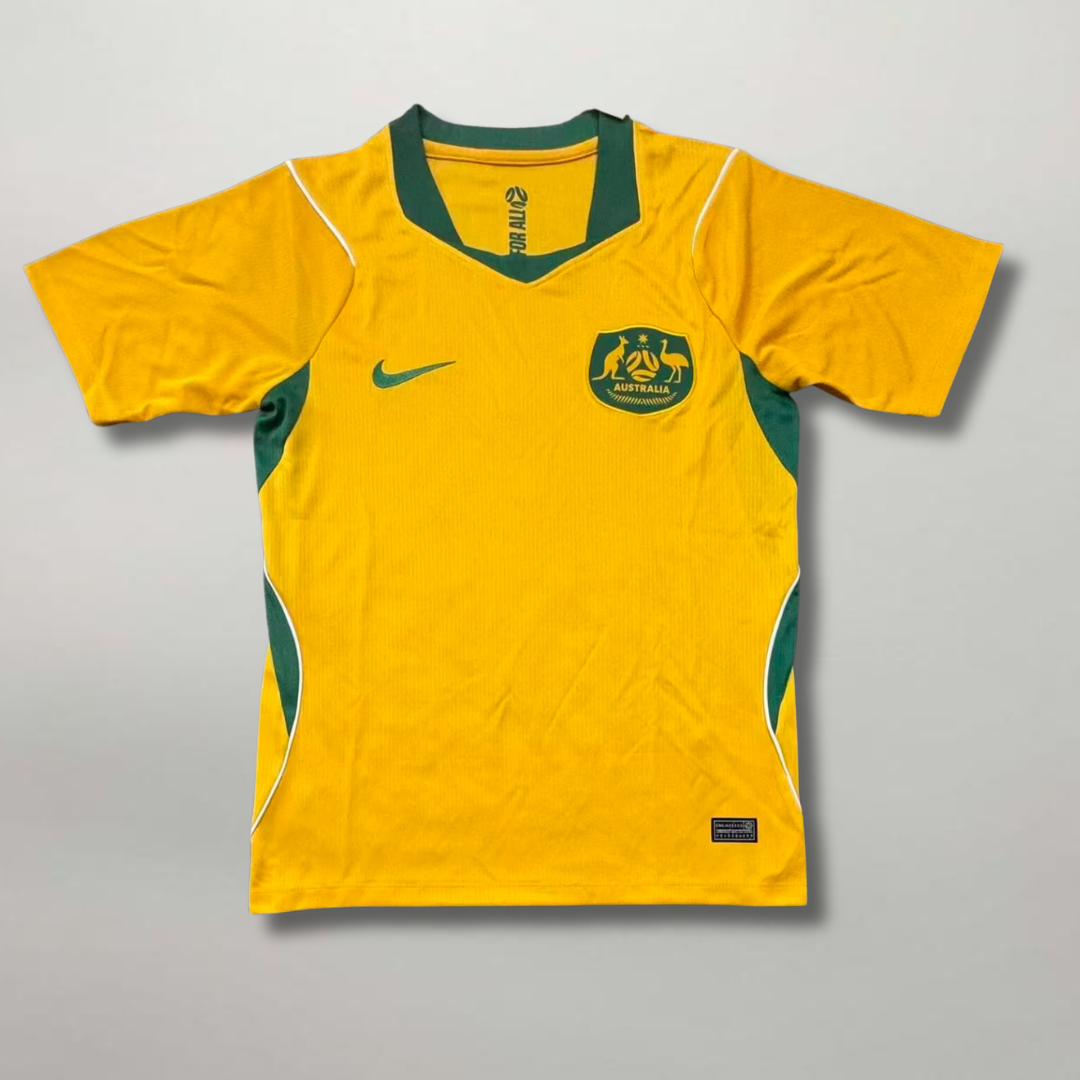 Fronte della maglia home dell'Australia 2026 oro con inserti verdi e stemma ufficiale ricamato sul petto