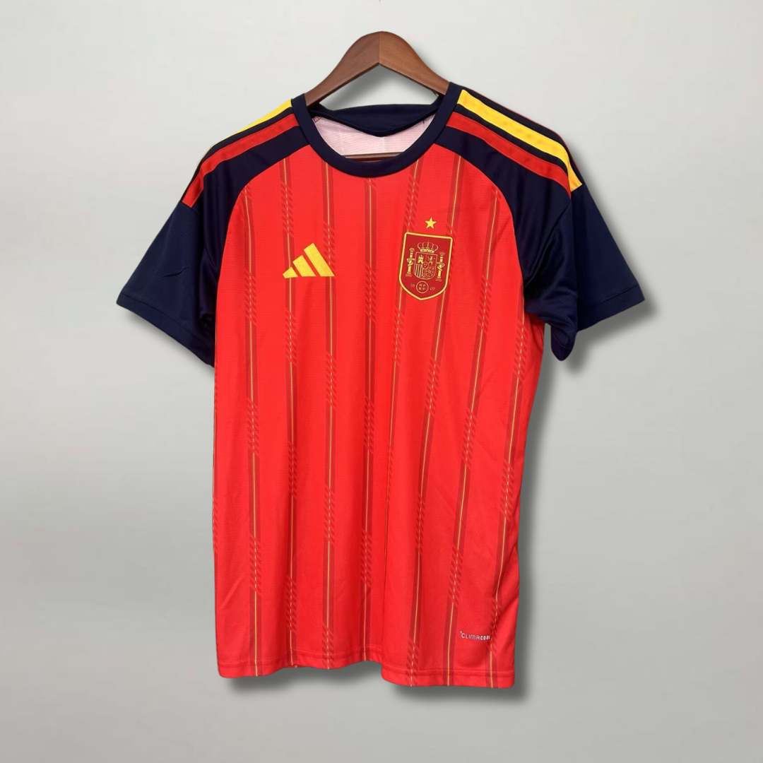 Fronte della maglia home della Spagna 2026 rossa con pannelli scuri sulle maniche e stemma sul petto