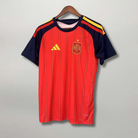 Fronte della maglia home della Spagna 2026 rossa con pannelli scuri sulle maniche e stemma sul petto