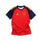Fronte della maglia home della Spagna 2026 rossa con pannelli scuri sulle maniche e stemma sul petto
