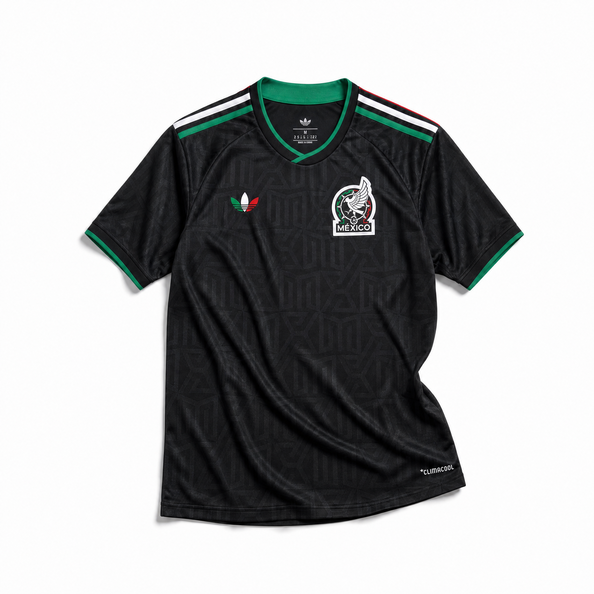 Maglia third Messico Coppa del Mondo 2026 — vista frontale su superficie in legno, colore nero con pattern geometrico azteco tono su tono, colletto rotondo con bordino tricolore verde-bianco-rosso e stemma nazionale sul petto sinistro