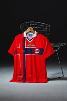 Norvegia Maglia Home 1997/98 World Cup appesa in esposizione con dettagli storici della divisa.