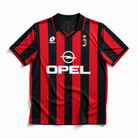 Fronte maglia rossonera Milan 1995/96 con strisce verticali e colletto a polo scuro.